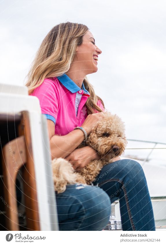 Cheerful woman caressing Poodle on yacht under cloudy sky poodle dog laugh canine animal pet eyes closed together companion smile cheerful chordate omnivore