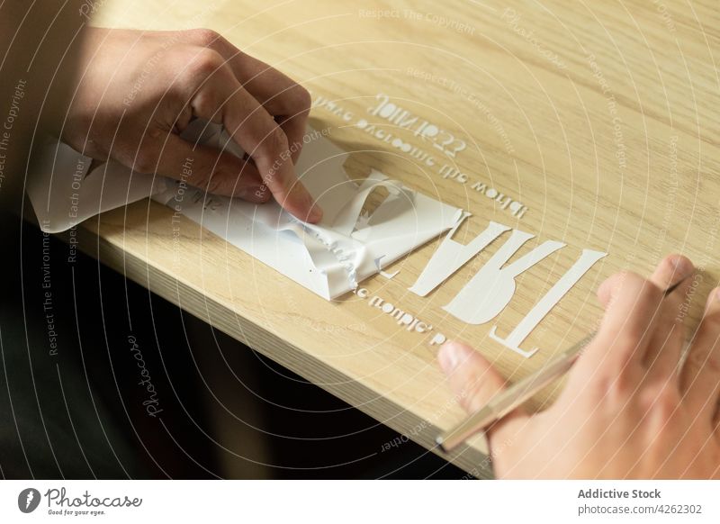 Crop unrecognizable person transferring cutout letters on transparent tape create paper process handmade workplace desk tool inscription sahrp creative draw