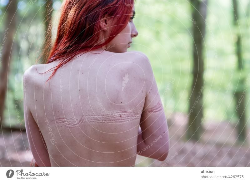 Back of young beautiful sexy woman with long hair in forest with imprints of tied rope from bondage on bare skin Abuse liberation scars constraints compulsions