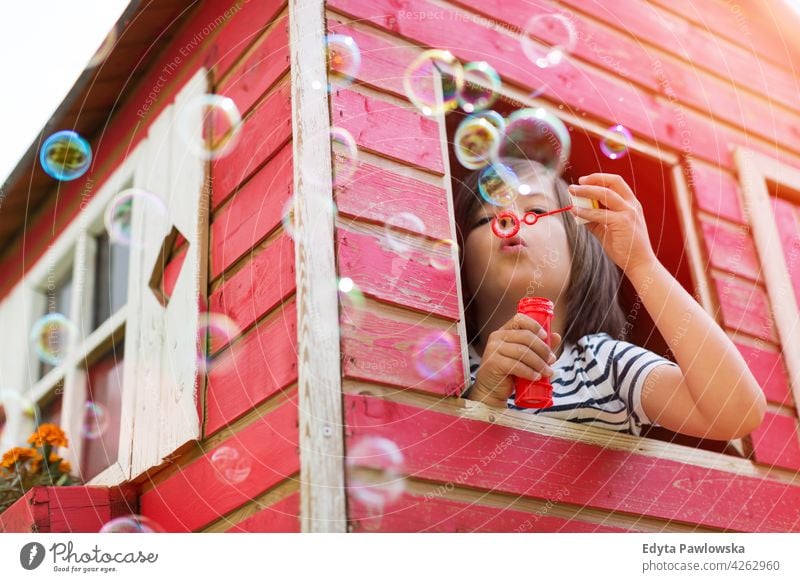 Boy blowing bubbles in a wooden playhouse red Sweden tree tree house treehouse summer outdoors adventure playful real people simple living playing sunny