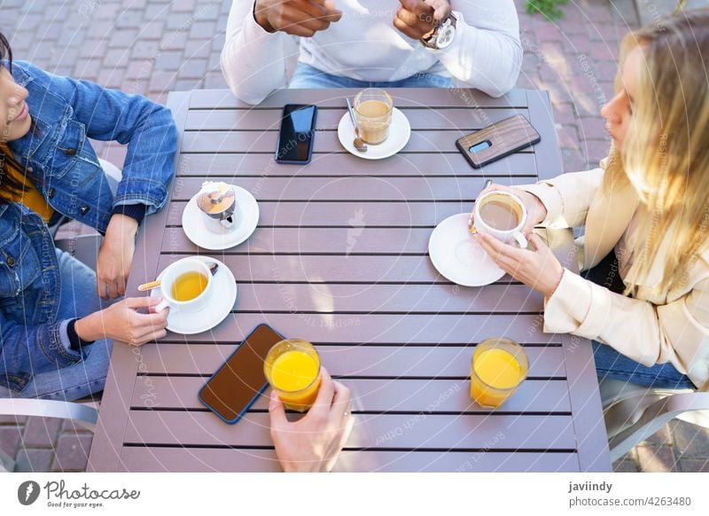 Top view of people drinking some beverages sitting at the table on the terrace of a bar. coffee cafe cup friends tea unrecognizable meeting smartphone lifestyle