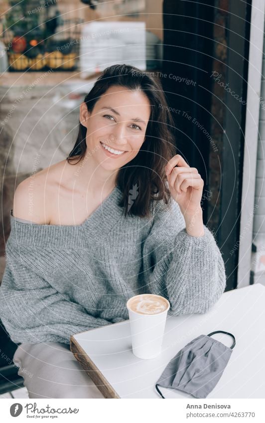 Young lady is drinking coffee at the cafe cup woman portrait young face mask smile lockdown lifted beautiful female casual brunette table happy person adult