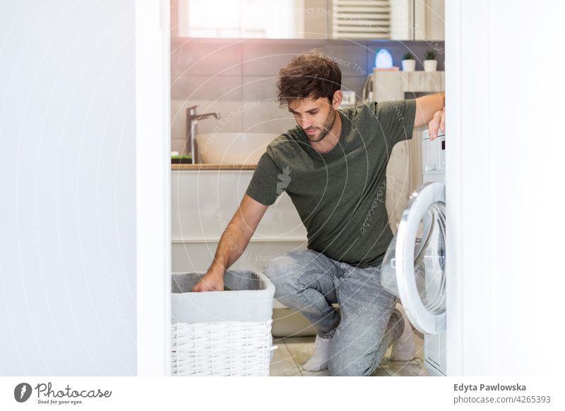 Man loading washing machine domestic casual home indoors apartment interior modern house man male people young young adult caucasian one person washer laundry