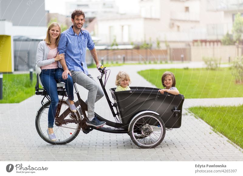 Young family having a ride with cargo bike tricycle day healthy lifestyle active outdoors fun joy bicycle biking activity cyclist enjoying bike ride modern
