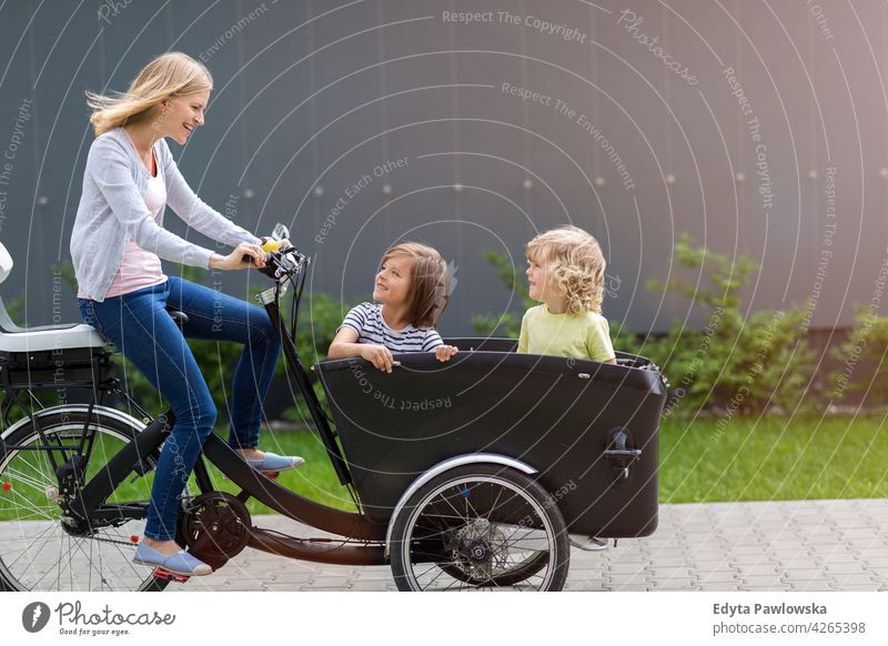 Mother and children having a ride with cargo bike tricycle day healthy lifestyle active outdoors fun joy bicycle biking activity cyclist enjoying bike ride