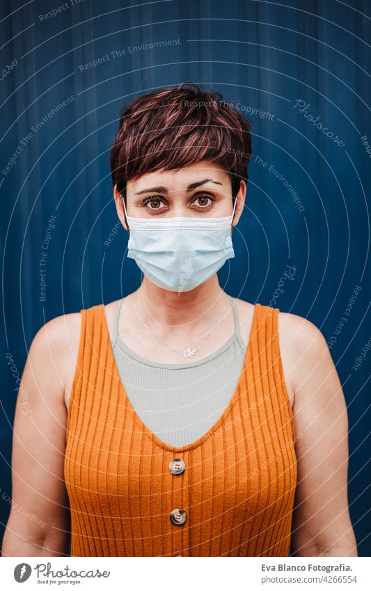 caucasian woman outdoors wearing face mask. Pandemic during corona virus social distance concept. portrait city urban casual clothing young beautiful orange