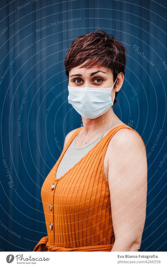 caucasian woman outdoors wearing face mask. Pandemic during corona virus social distance concept. portrait city urban casual clothing young beautiful orange