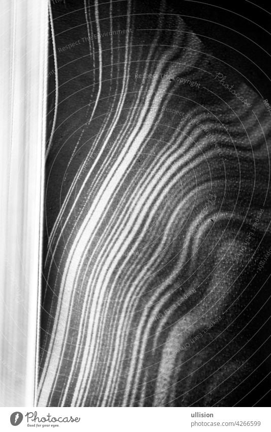 Detail of the body of a young beautiful woman, attractive, sexy, naked, with striped shadows by the white threads of a falling curtain of threads, which forms the body beautifully.