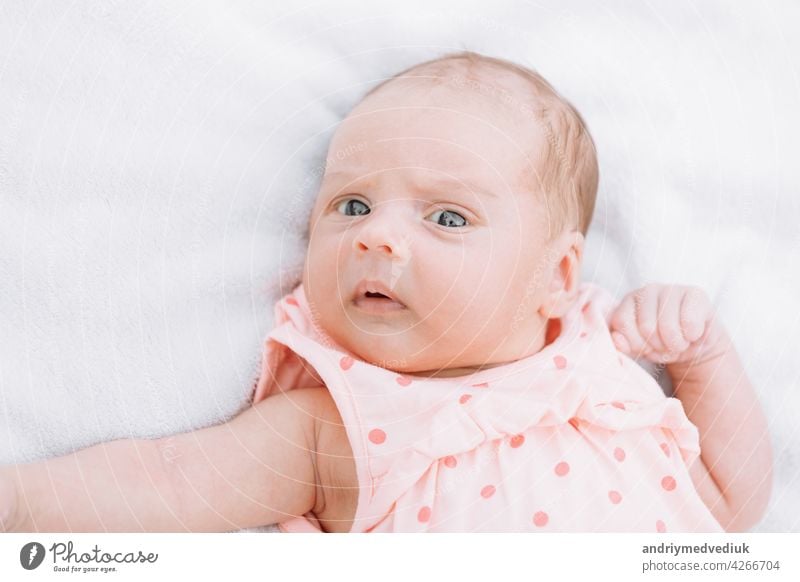 Newborn baby girl on grass in the park outdoors, lies on a white blanket looking around. selective focus. little childhood adorable infant cute newborn sweet