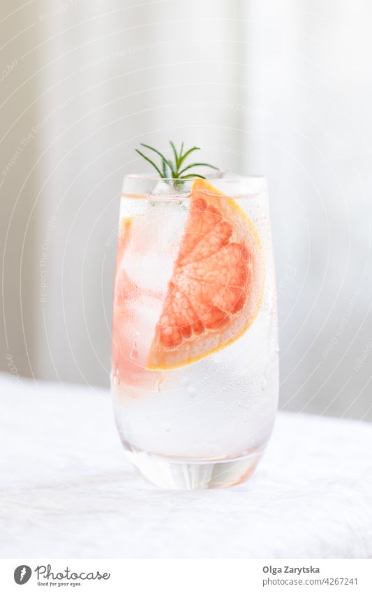 Cold water with grapefruit. drink cold lemonade ice rosemary summer glass refreshment citrus perspiration beverage white minimal cocktail background cool