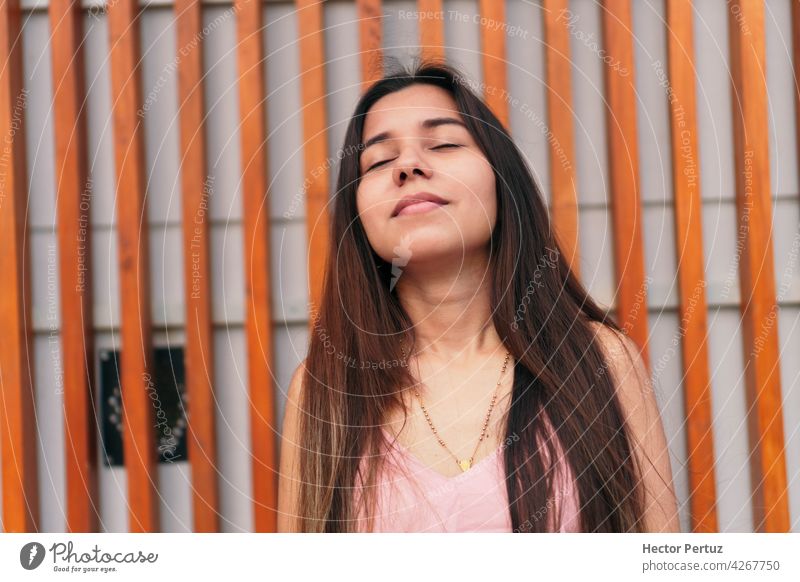 Young beautiful woman with her eyes closed in the street female portrait young adult casual latina american brunette hispanic people happy person freedom