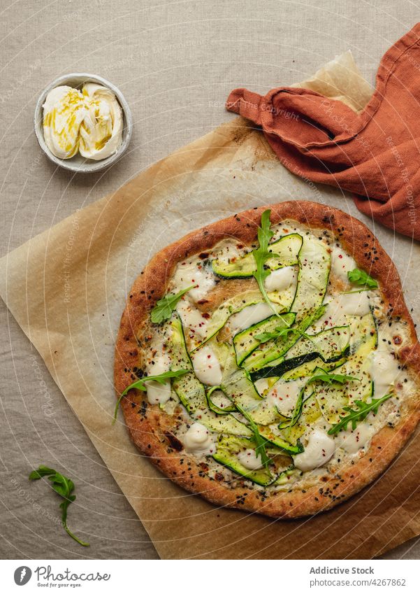 Delicious pizza with zucchini slices on melted mozzarella cheese squash arugula lunch dinner meal food tasty parchment paper appetizing sesame seasoning baked