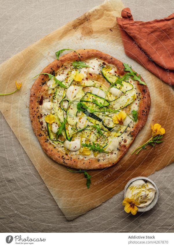 Delicious pizza with zucchini slices on melted mozzarella cheese squash arugula lunch dinner meal food tasty parchment paper appetizing sesame seasoning baked