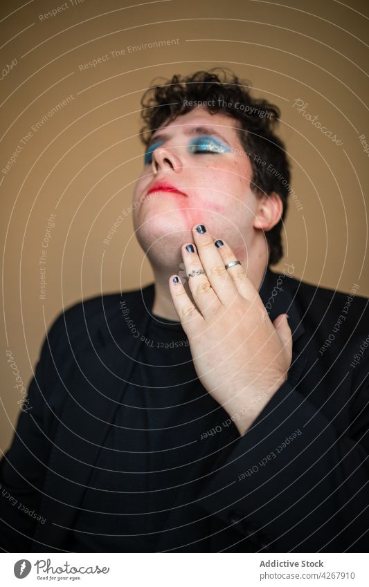 Alluring man with bright makeup touching lips sensual queer transgender seductive provocative eccentric unusual male transsexual extraordinary extravagant lgbtq