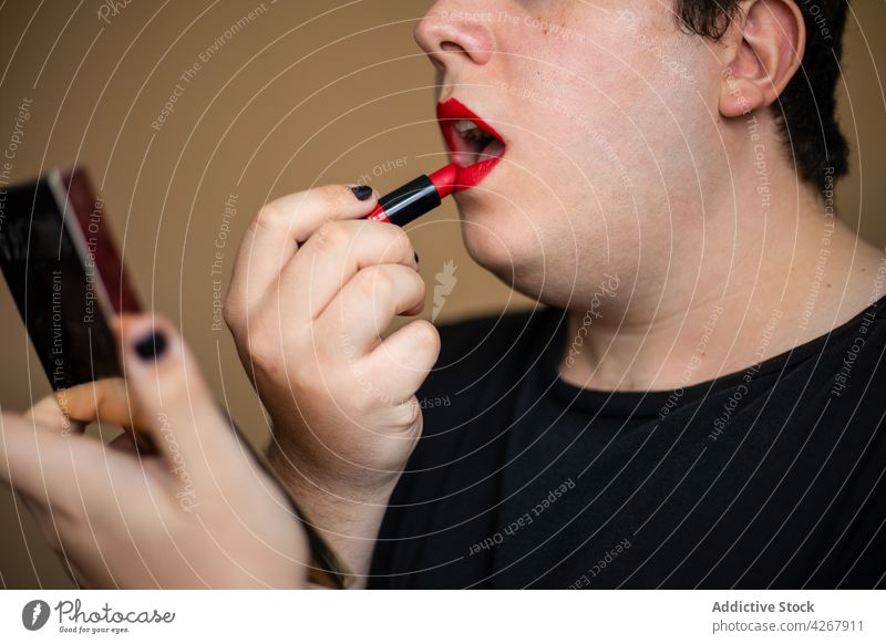 Overweight male with mirror applying red lipstick man cosmetic cosmetology transgender makeup visage androgynous queer extravagant transsexual unusual process