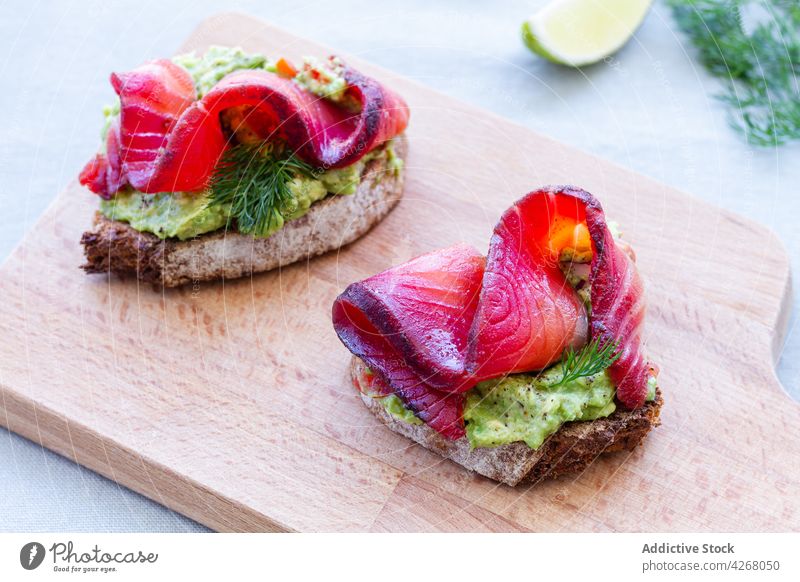 Delicious toasts with guacamole and gravlax on cutting board appetizer delicacy fish salmon protein delicious smoked similar starter dill cured fresh herb