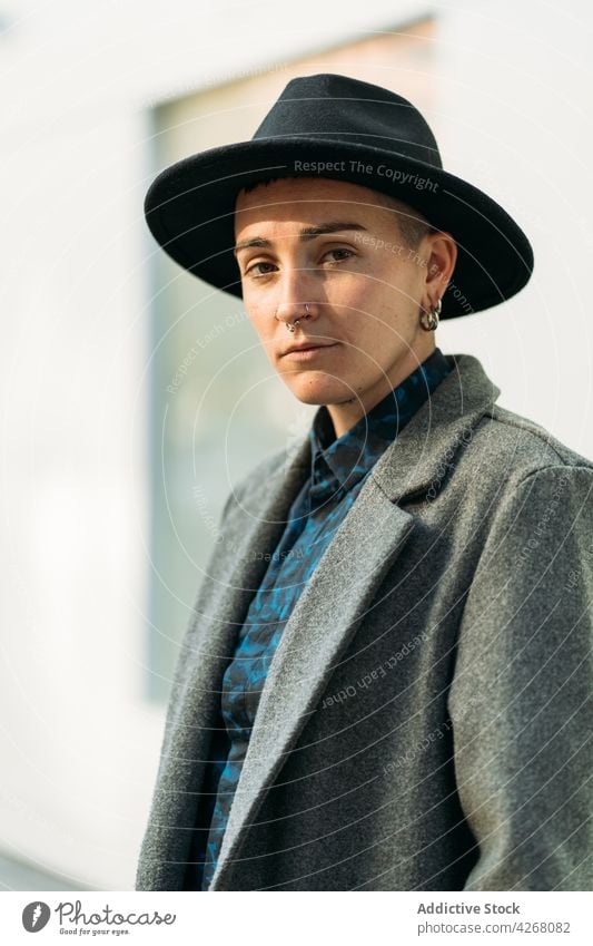 Queer in stylish outerwear standing outdoors transgender person style fashion individuality accept identity tattoo portrait queer androgynous sincere modern