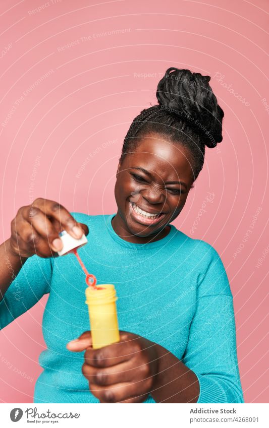 Joyful black woman blowing soap bubbles in studio ethnic joyful african american happy colorful vivid playful toy having fun smile entertain positive cheerful