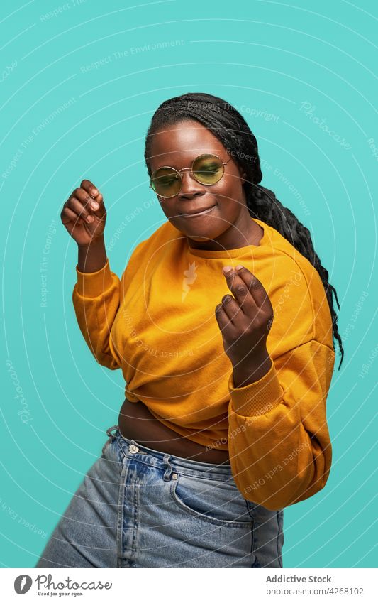 Content black woman dancing happily on blue background dance happy cheerful style outfit trendy vivid energy cool entertain optimist colorful sunglasses