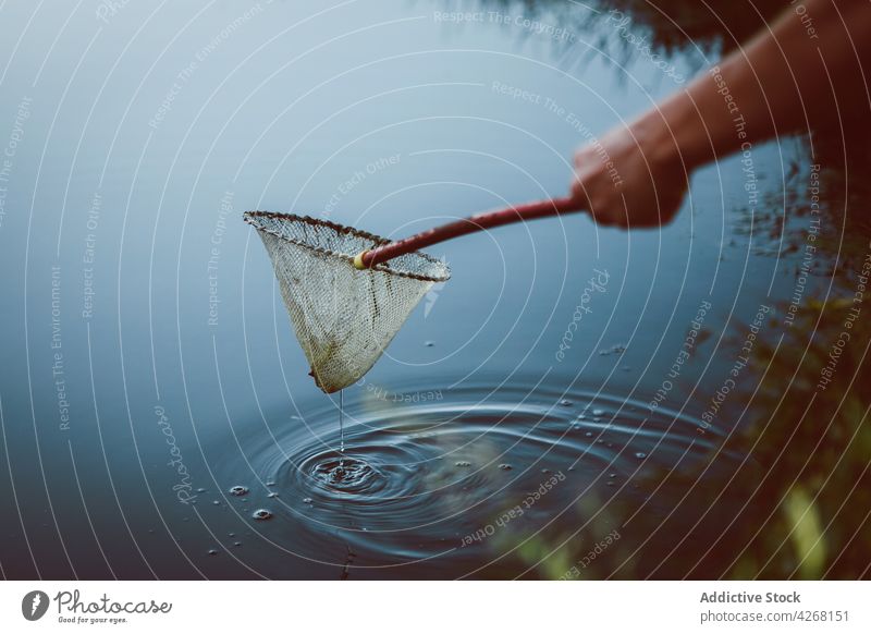 Crop person with scoop net catching fish in river nature weekend pastime ripple process water aqua pure wavy spare time stream stick idyllic free time fluid
