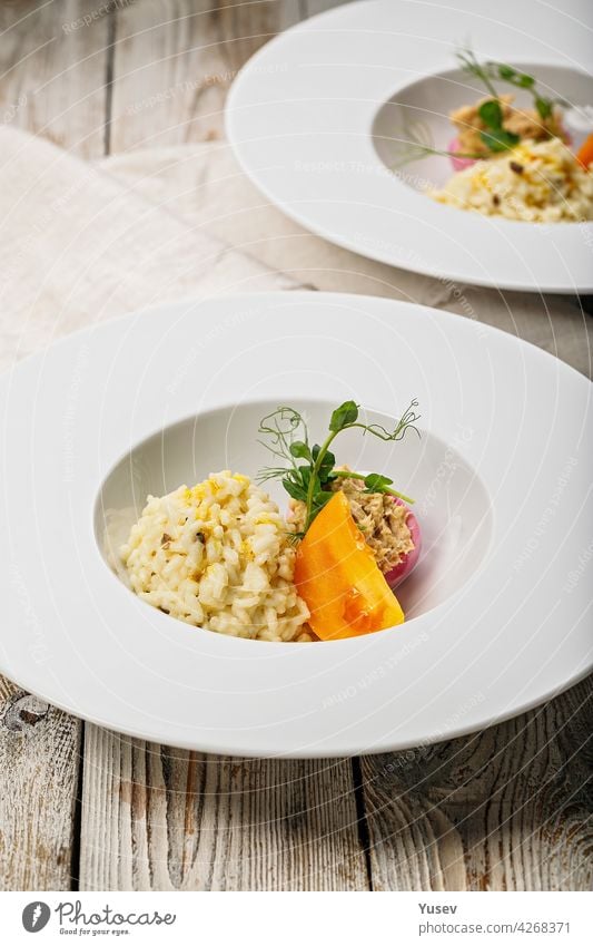 Risotto with seafood. Egg with smoked mackerel pate. Honey orange tomato. Gourmet cuisine. Food photography and styling. Mediterranean Kitchen. Vertical shot. Close-up. Delicious and healthy eating