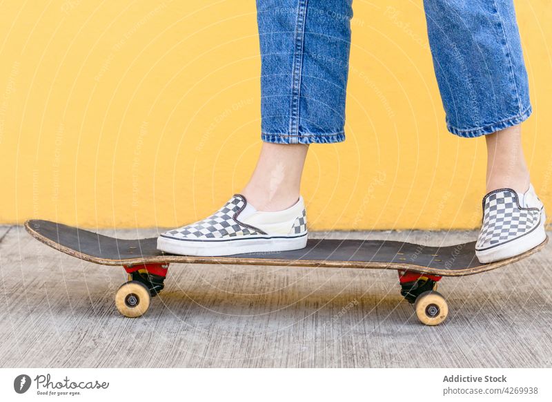 Anonymous skateboarder in casual apparel on pavement on yellow background skater cool contemporary generation spare time lifestyle teen equipment sport footwear