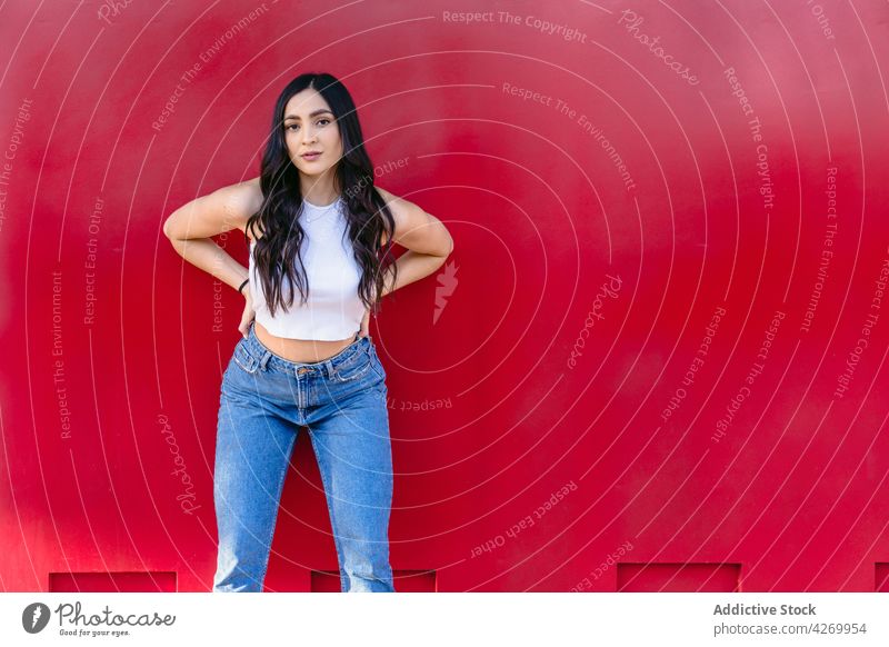 Emotionless teen standing on red background teenage feminine pleasant casual style sincere wall outfit adolescent gentle tender female contemporary charismatic