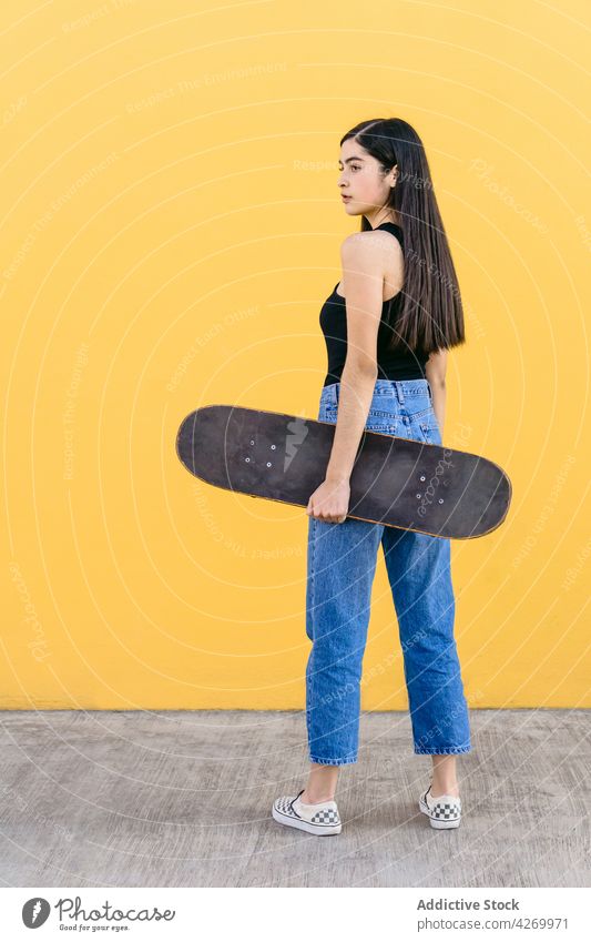 Skateboarder in casual apparel on pavement on yellow background skater skateboard cool contemporary generation spare time lifestyle teen equipment sport