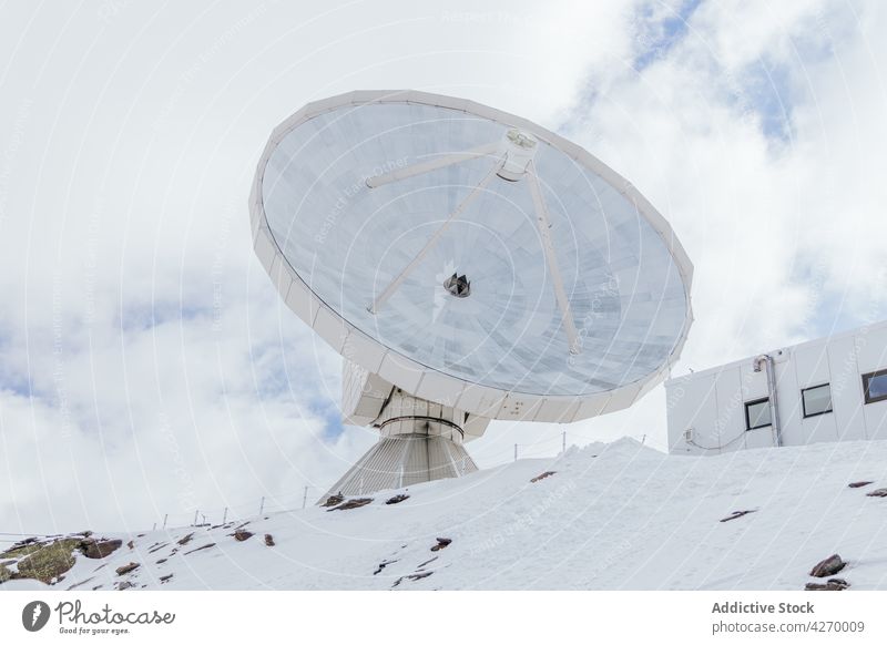 Observatory on snowy ridge against house exterior in ski resort observatory satellite antenna receiver transmitter radio wave building mountain sky cloudy