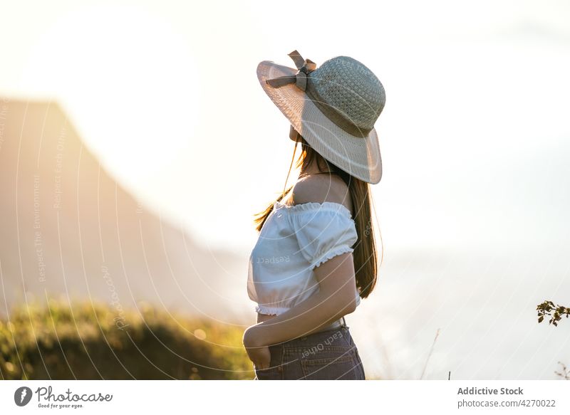 Woman with hat brim and standing on verdant grassy countryside woman lawn dreamy peaceful summer style sensitive nature serene meadow trendy appearance tranquil