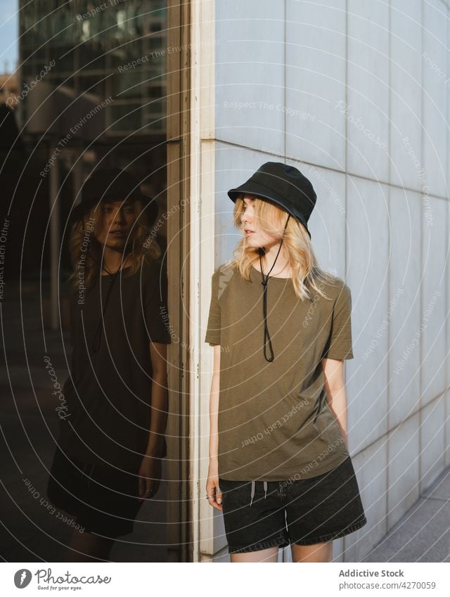 Millennial woman reflecting on glass wall in town reflection individuality style casual feminine gentle lifestyle urban tender romantic wistful dreamy