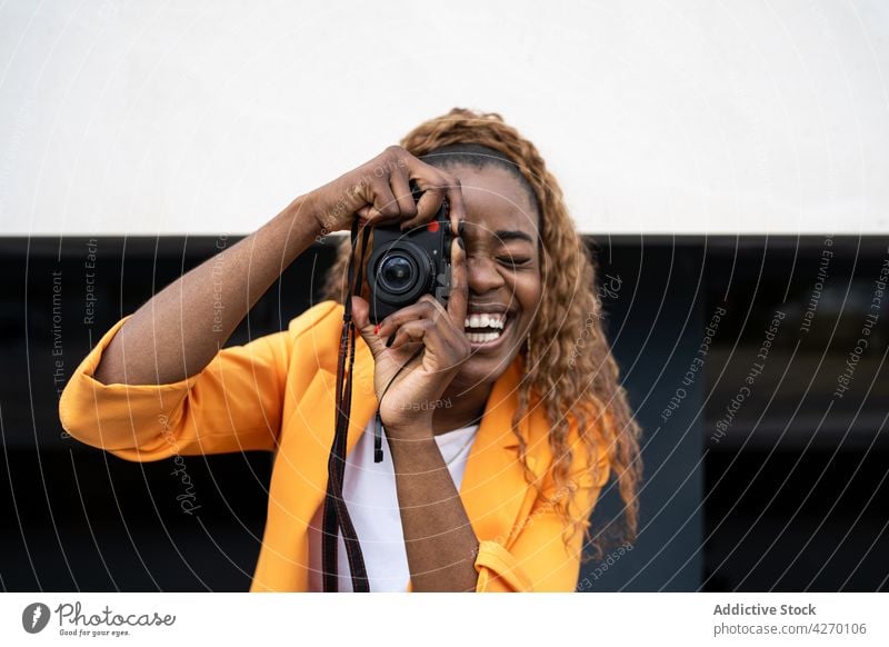 Black cheerful woman taking photo on camera laugh enjoy leisure happy take photo photo camera fun capture hobby female optimist gadget memory sincere glee