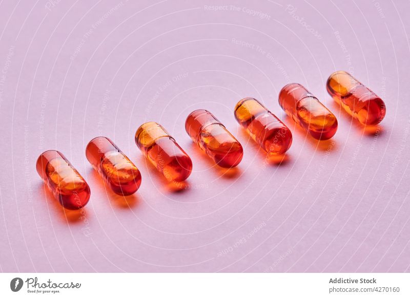 Orange pills on pink surface drug medication capsule cure composition orange remedy vitamin treat pharmacy health care concept colorful pharmaceutical