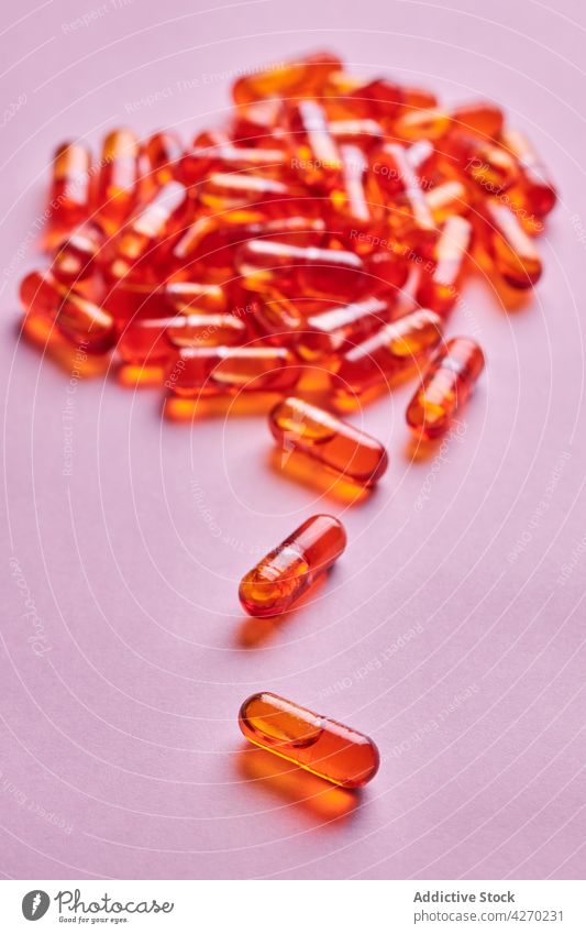 Orange pills scattered on pink surface drug medication capsule cure composition orange remedy vitamin treat pharmacy health care concept colorful pharmaceutical