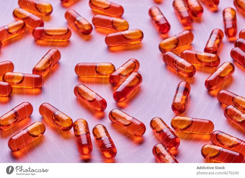 Orange pills scattered on pink surface drug medication capsule cure composition orange remedy vitamin treat pharmacy health care concept colorful pharmaceutical