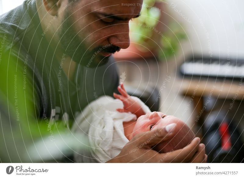 Father looking at newborn child. father parent dad pop beard person of color latino hispanic litinx man poc hand hands baby infant kid small tiny stare gaze