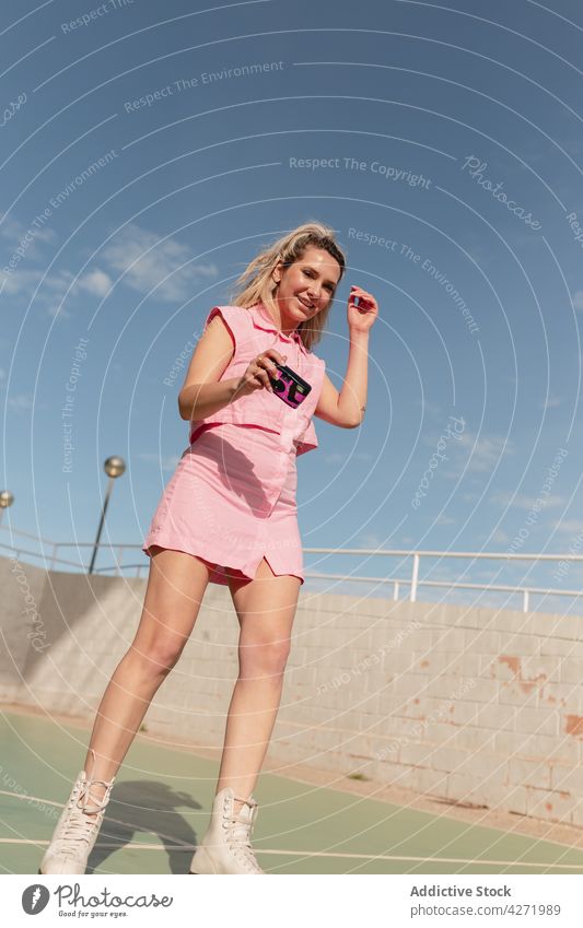 Cheerful woman on roller skates taking photo on instant camera skater take photo cheerful photography sports ground activity hobby style blonde memory joy
