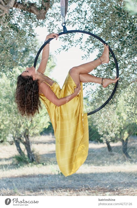 Young gymnast posing on a aeriel circle woman pose athletic garden olive tree green dress sport air hoop training dance fitness outdoor elegance gymnastics