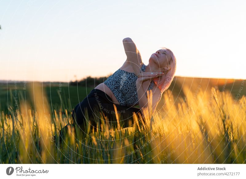 Woman performing Crescent Lunge with Prayer Hands pose in field woman crescent lunge prayer hands side bend yoga wellness energy vitality healthy lifestyle