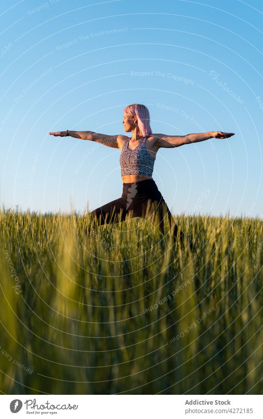 Woman standing in Warrior pose in countryside field woman warrior pose yoga healthy lifestyle wellbeing vitality energy outstretch practice wellness meadow