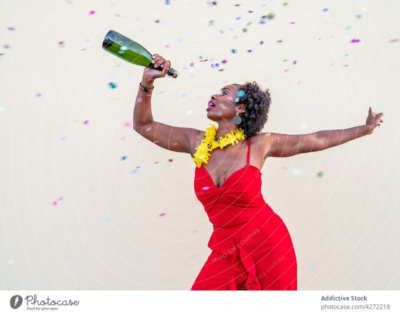 Happy black woman with glass bottle of champagne happy cheerful holiday celebrate joy event excited female alcohol elegant fun festive glad occasion laugh