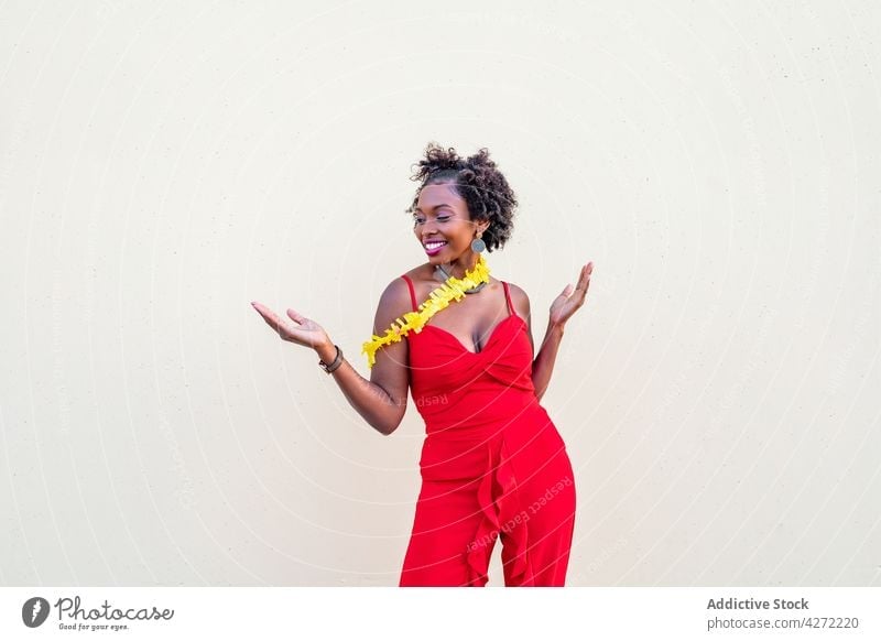 Happy African American woman standing near white wall holiday celebrate laugh amazed female fun expressive positive delight carefree festive bright event joy