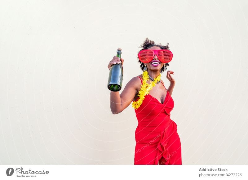Happy black woman in stylish wear with bottle of champagne celebrate party style fashion happy drink alcohol glasses red apparel earring accessory trendy