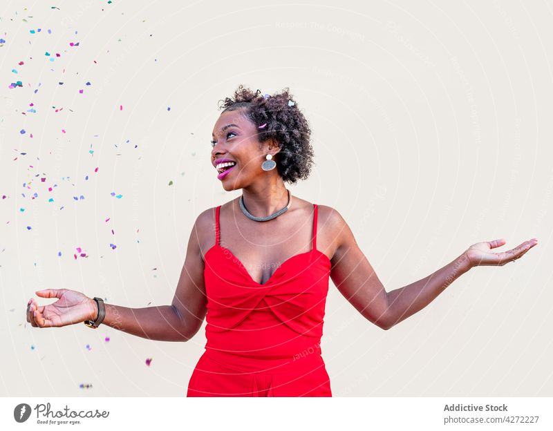 Happy African American woman standing under confetti during celebration happy fall holiday celebrate excited laugh amazed surprise female fun expressive