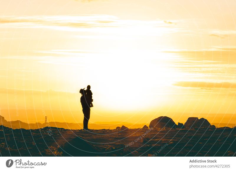 Unrecognizable father holding son in air in desert at sunset man child rocky valley together male boy sundown bright kid countryside fatherhood childhood