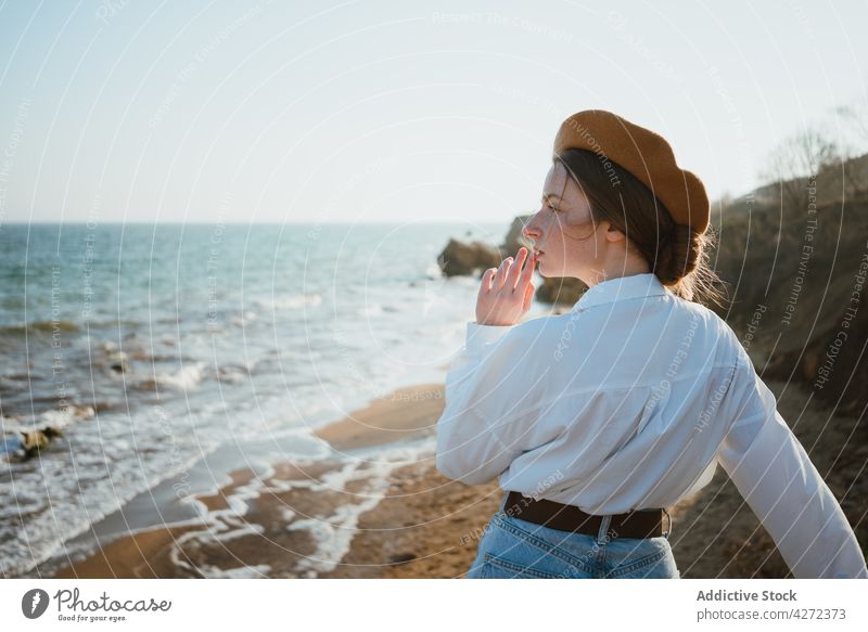 Romantic young lady enjoying view of ocean on sandy beach woman admire sea seashore dreamy traveler style nature recreation vacation female trendy beret pensive