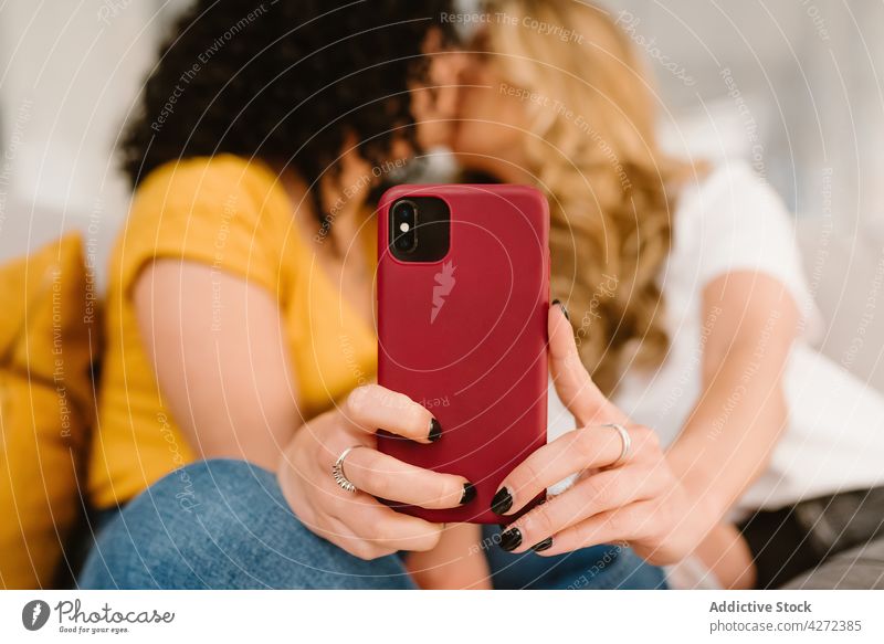 Crop loving lesbian couple kissing and taking selfie women relationship love lgbt smartphone romantic together affection bonding device tender girlfriend