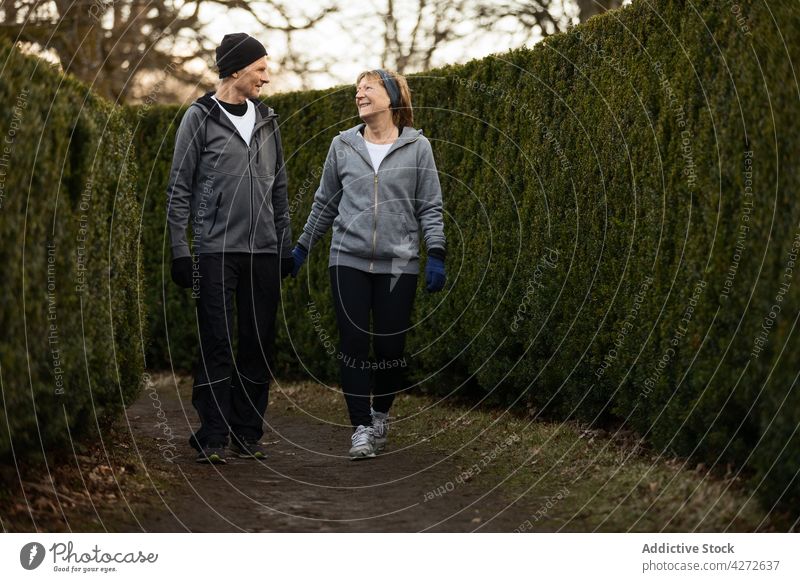 Positive elderly couple walking together in park senior run training fitness cardio activity active positive man woman wellbeing healthy sport sportswear