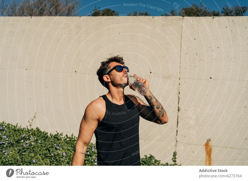 Sportsman drinking water after workout in town athlete thirsty refreshment sporty masculine tattoo muscular bottle sunglasses enjoy aqua liquid hydrate