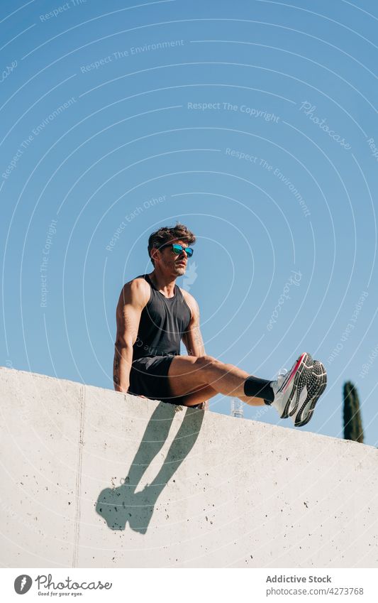 Sportsman working out on fence under blue sky sportsman training workout exercise strong bicep masculine cloudless sneakers shadow strength athlete practice
